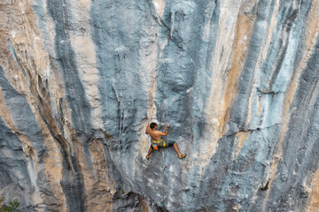 Extreme sport, strong man, rock climber climbs a difficult route.