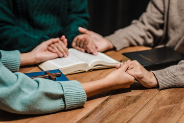 Obraz premium A group of people sits together, reading the Bible and praying. Their expressions reflect deep faith and friendship, creating a serene atmosphere filled with love, hope, and spiritual connection.