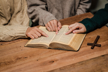 A group of people sits together, reading the Bible and praying. Their expressions reflect deep faith and friendship, creating a serene atmosphere filled with love, hope, and spiritual connection.