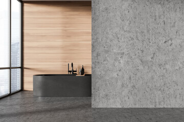 Modern minimalist bathroom with a black bathtub and concrete floors. Light wood wall with a large window. Concept of minimalist home design. 3D rendering.
