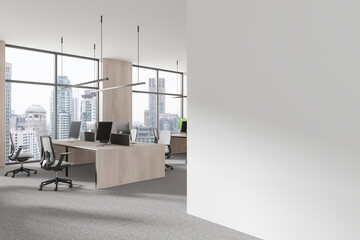 Сoworking interior with desks and pc monitors, panoramic window. Mockup wall