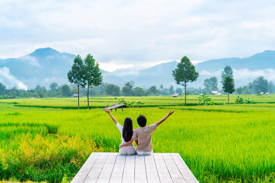 Young happy couple tourist enjoying and relaxing at rice paddy field while traveling at Nan, Thailand
