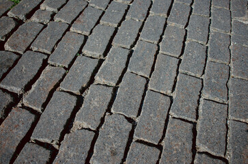 The texture of dark paving stones. Top view of the cobblestone pavement. An old stone sidewalk. The texture of the paving stones. The background is made of cobblestones, the road is made of cobbleston