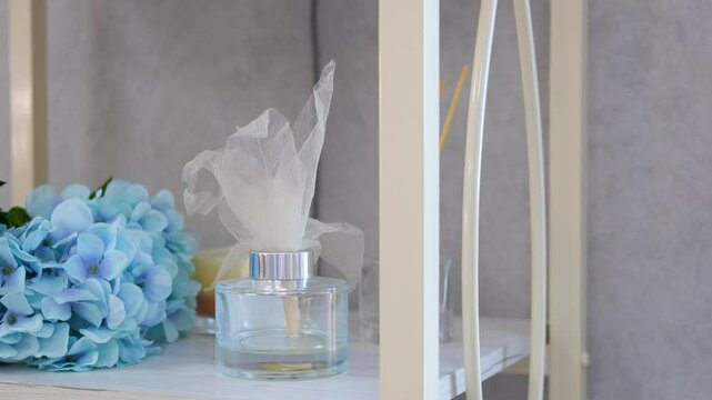 Perfume flavor. Aroma scented reed diffuser glass is on the tray with scented candle on the bed 