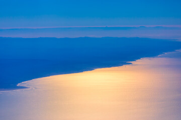 Fototapeta premium Flight over Atlantic Ocean and Morocco coast. Aerial view of ocean waves meeting majestic mountains in a scenic landscape