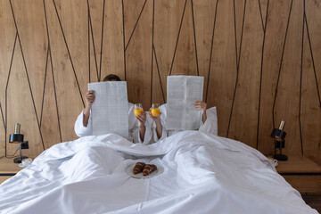 couple reading newspapers in the hotel bed