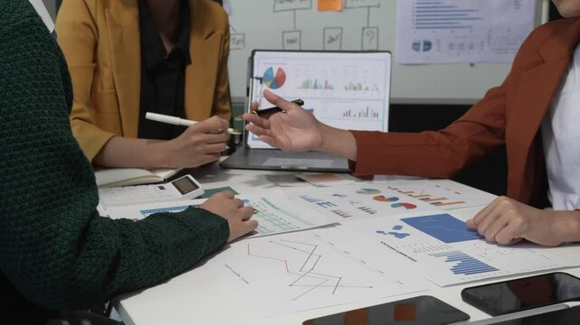 A group of people collaborates around a desk, discussing and reviewing user interface (UI) and user experience (UX) elements. usability, accessibility, and design principles for product development.
