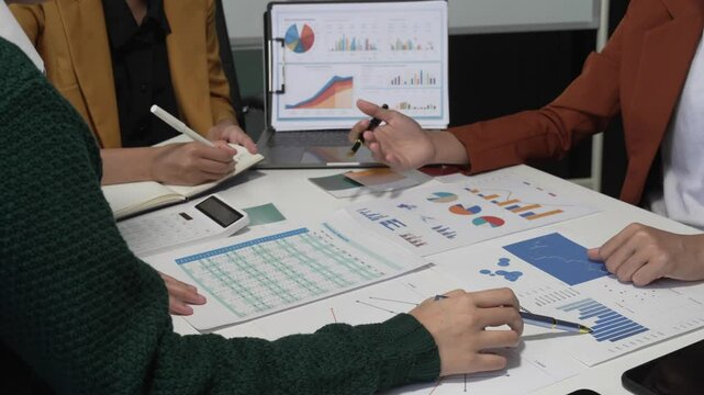 A group of people collaborates around a desk, discussing and reviewing user interface (UI) and user experience (UX) elements. usability, accessibility, and design principles for product development.