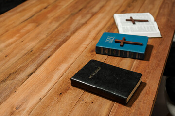 An open Bible lies on a wooden desk, symbolizing faith and spirituality. The pages are spread, inviting contemplation and study in a serene, wooden environment.