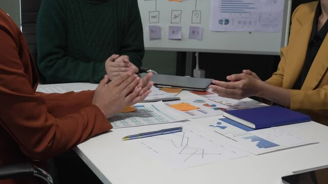 A group of people collaborates around a desk, discussing and reviewing user interface (UI) and user experience (UX) elements. usability, accessibility, and design principles for product development.