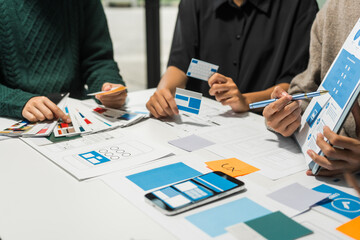 A group of people collaborates around a desk, discussing and reviewing user interface (UI) and user experience (UX) elements. usability, accessibility, and design principles for product development.