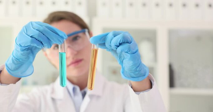 Lab technician compares tubes with different colored liquids. Female scientist seeks to discern significant differences or similarities
