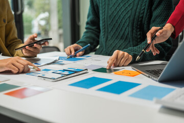 A group of people collaborates around a desk, discussing and reviewing user interface (UI) and user experience (UX) elements. usability, accessibility, and design principles for product development.
