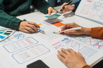 A group of people collaborates around a desk, discussing and reviewing user interface (UI) and user experience (UX) elements. usability, accessibility, and design principles for product development.