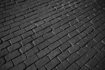 The texture of dark paving stones. An old stone sidewalk. The texture of the paving stones. The background is made of cobblestones, the road is made of cobblestones.