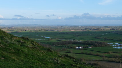 Fototapeta premium Scenic view from The Tor overlooking green agricultural farmland and fields of the Somerset Levels in West Country of England UK