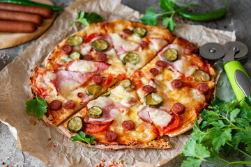 Pizza slices on a gray background. Italian pizza with mozzarella, ham, cucumbers and salami. Close-up.