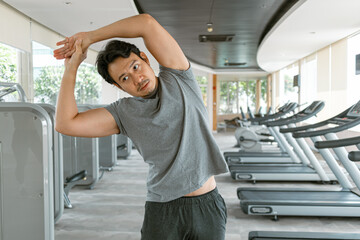 Fitness asian Thai man stretching after done exercise, building muscles workout at gym, routine in the morning.