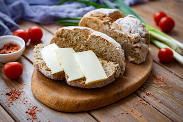 Homemade rye bread on a wooden background. A buttered sandwich made from homemade bread. A sandwich of rye bread with butter. Close-up