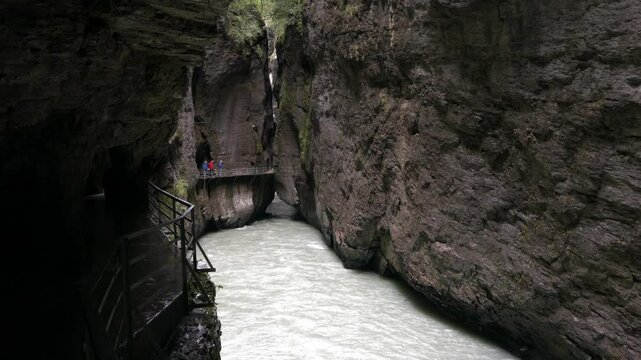 A narrow tunnel with a river running through it. The tunnel is dark and the water is clear