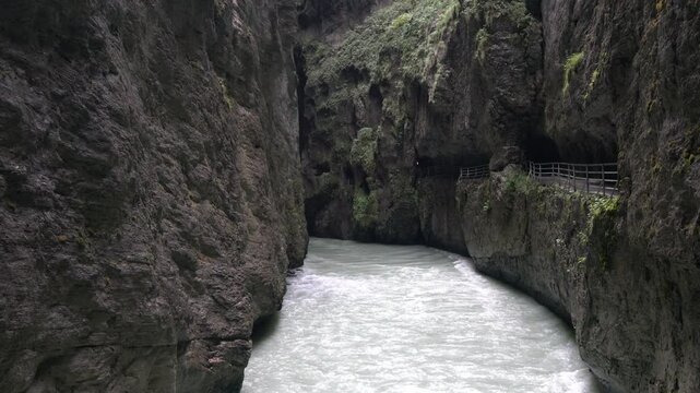 A narrow tunnel with a river running through it. The tunnel is dark and the water is clear
