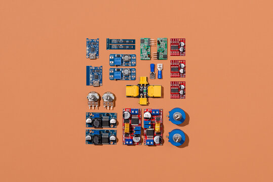 Microcontrollers, boards, sensors, leds and modules for learning the basics of electronics. Various electronic components for soldering arranged in creative arrangement on orange background