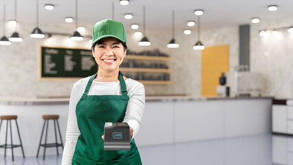 Asian seller wear green apron and green cap smiling with hand holding card reader