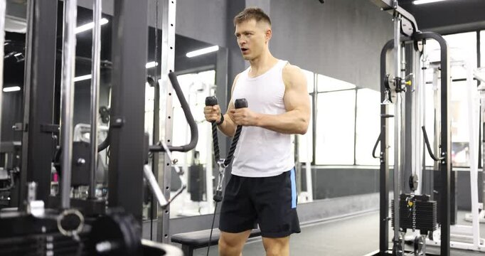 Young sportsman performs intense workout for biceps in gym. Man maintains tension in muscles to maximize effectiveness of exercise slow motion