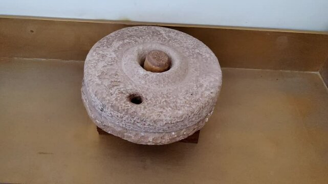 The ancient hand mill or quern stone, grinds the grain into flour. Old handmade grinding stones. An ancient hand mill made of stones and wood. Flour grinding device. Authentic handicraft.