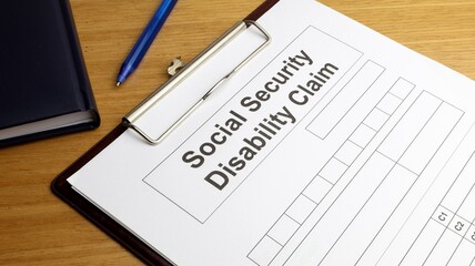 Disability claim form social security desk with agenda and pen.