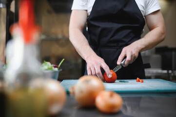 Chef of a Big Restaurant Prepares Dishes. Modern Kitchen is Made of Stainless Steel and Full of Cooking Ingredients