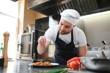 Chef salt slice vegetables and meat. Concentrated chef prepare food. Professional male cook healthy food at commercial restaurant