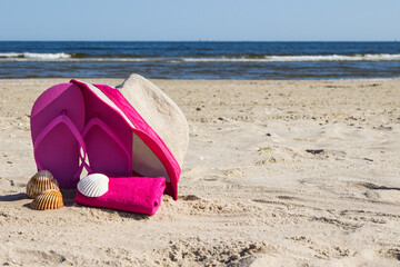 Flip flop, straw hat and towel on beach. Accessories for relax on sand. Summer vacation