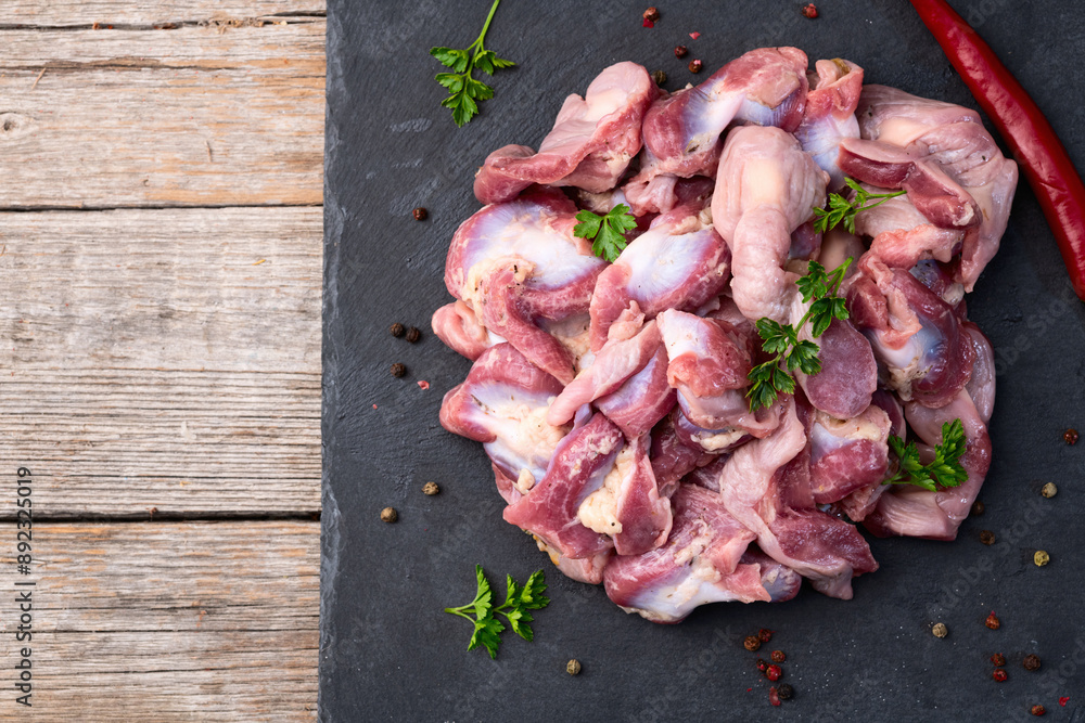 Poster raw chicken giblets gizzard ( stomach ) , meat background