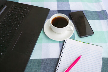 Working with a notepad, laptop, coffee in a restaurant cafe setting with plants. Java Americano