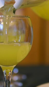 Pour orange juice Squeezing juice from half a tangerine to the glass by hand pressure, view on a background of other whole tangerines on a table