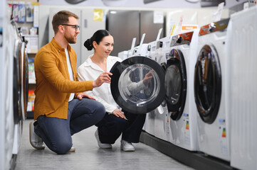 Young couple choosing washing machine in hypermarket.
