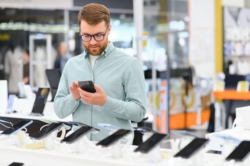 guy in an electronics store chooses a cell phone to buy