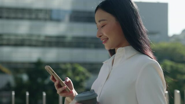 Side View of the Charming Happy Female Manager Walking Home After University and Using Smartphone, Scrolling Aps Outside.