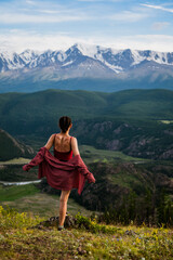 Naklejka premium girl in a red shirt looks at the peaks of snow-capped mountains