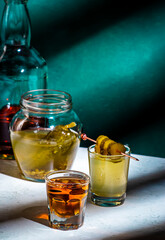 Alcoholic cocktail drink from cucumber pickle and whiskey in shot glasses. Dark green background