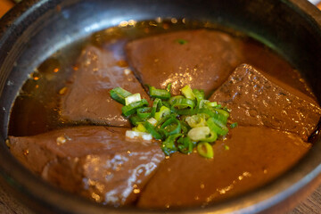A hearty serving of duck blood tofu sits in a steaming hotpot, enriched with flavorful broth and a medley of spices. This authentic Asian delicacy boasts a silky texture and rich, savory taste