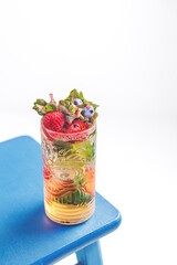 a refreshing cocktail in a glass decorated with mint leaves, strawberries and blueberries. Summer drink, heat, rest. Party. Cocktail in the pool. Summer vibe.