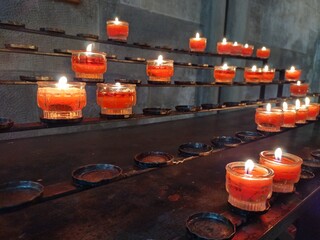 Burning candles in church. Religious theme, death, grief, remembrance, faith, hope, praying. Ritual of lighting a candle. Keeping a light burning in remembrance signifies that memory still lives on.
