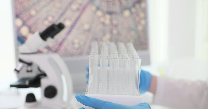 Laboratory worker moves stand with flasks along table. Person in rubber gloves places equipment around perimeter of workspace slow motion