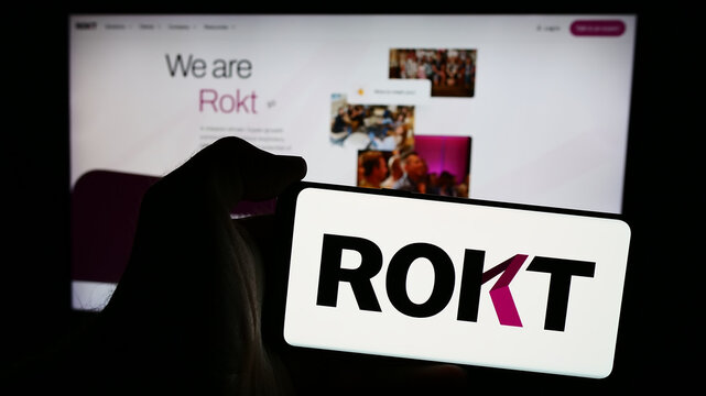 Stuttgart, Germany - 07-14-2024: Person holding mobile phone with logo of e-commerce technology company Rokt Pte. Ltd. in front of business web page. Focus on phone display.