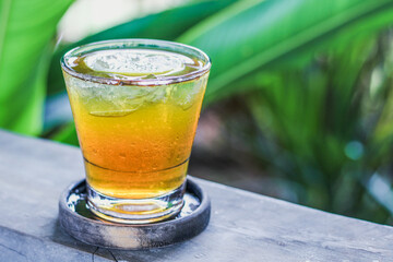 iced lemon tea with tropical plant in the background