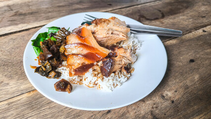 Stewed Pork leg rice, pickled vegetables, Thai food on plate, wooden table