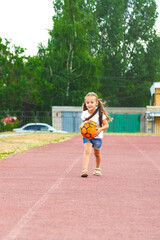 Little girl playing with a soccer ball on outdoor sports fields