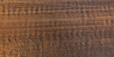view from above on texture of dry muddy road with tractor tire tracks in countryside